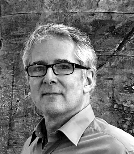 Schwarz-weiß-Porträt von Stefan Kemna, Designer der Cartes-Bilderleiste: Freundlich blickender Mann mit Brille vor Steinwand